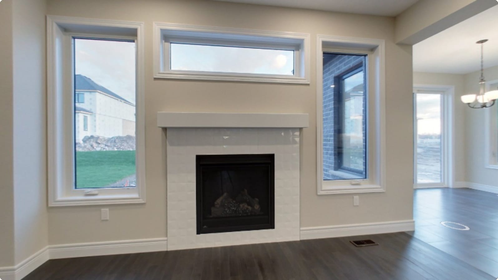 The same living room finished and empty, fireplace and windows in — opening view of the post-drywall stage